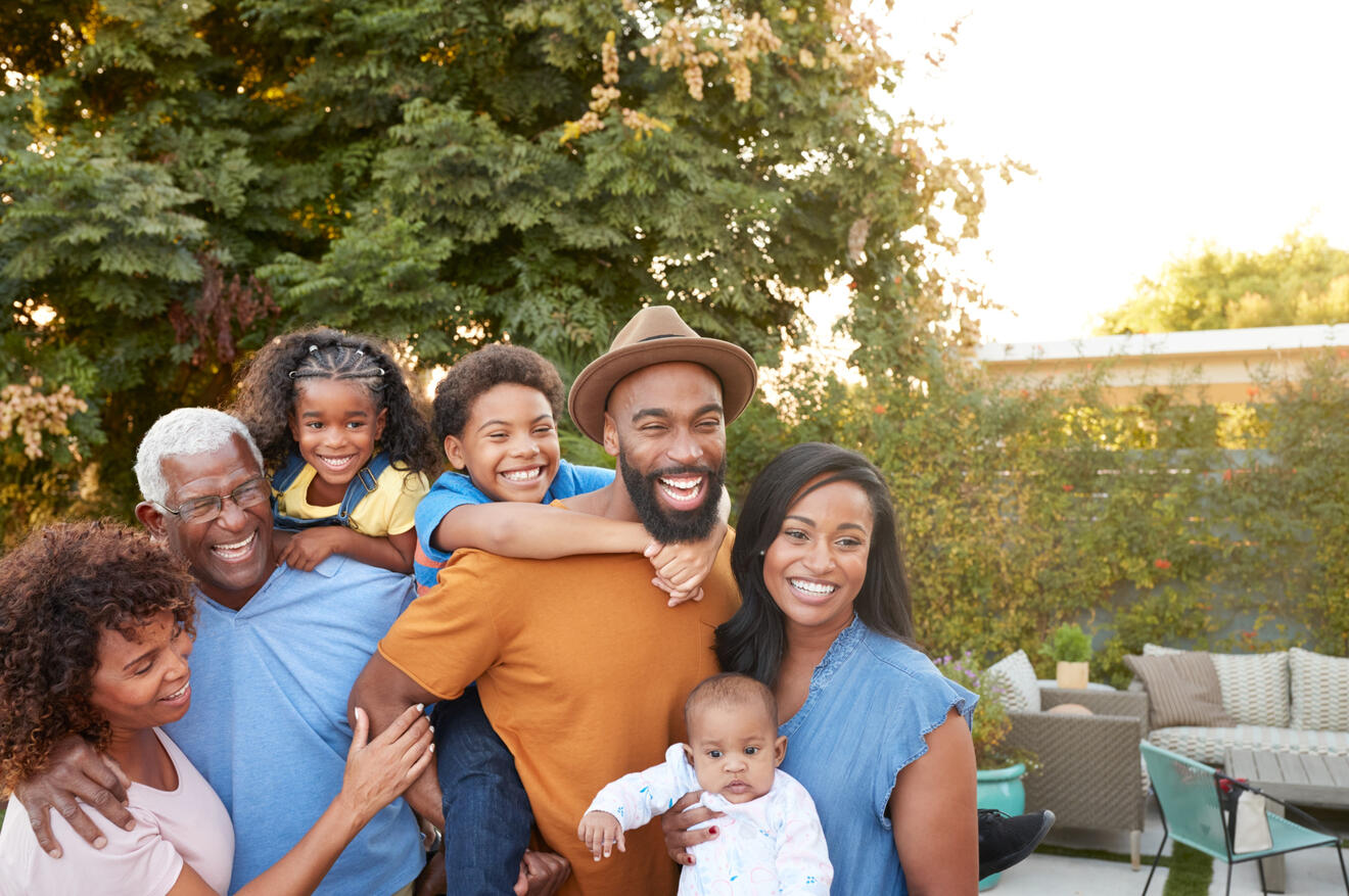 Black family of 6, with a daughter on the back of the grandfather and the son on the back of the father.