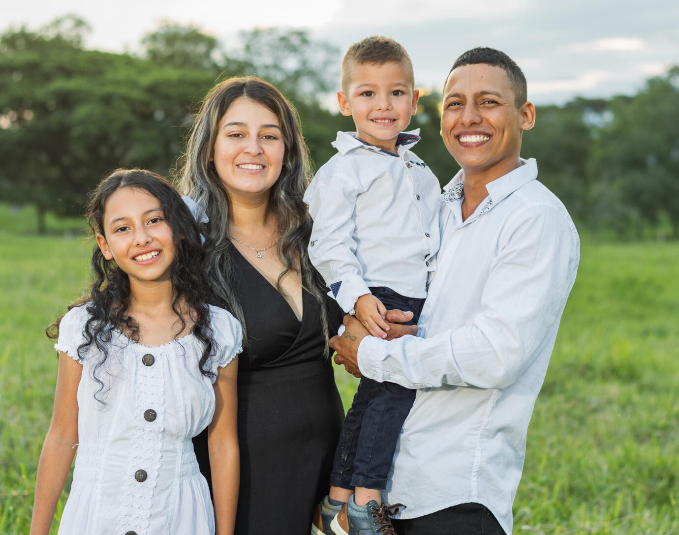 Hispanic family of 4, with dad holding the son.